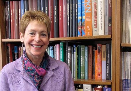 Denise Ney standing in front of a full bookcase