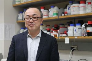 Glen Kwon standing in front of shelves of medication