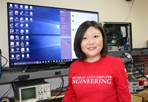 Jing Li standing in front of monitor and computer equipment