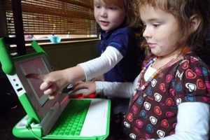 Two small kids playing on a computer